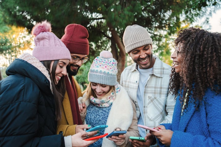 grupo-de-jovenes-sonriendo-y-compartiendo-con-sus-celulares