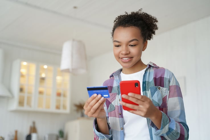 mujer-joven-con-tarjeta-en-la-mano-y-celular-realizando-transferecia-bancaria