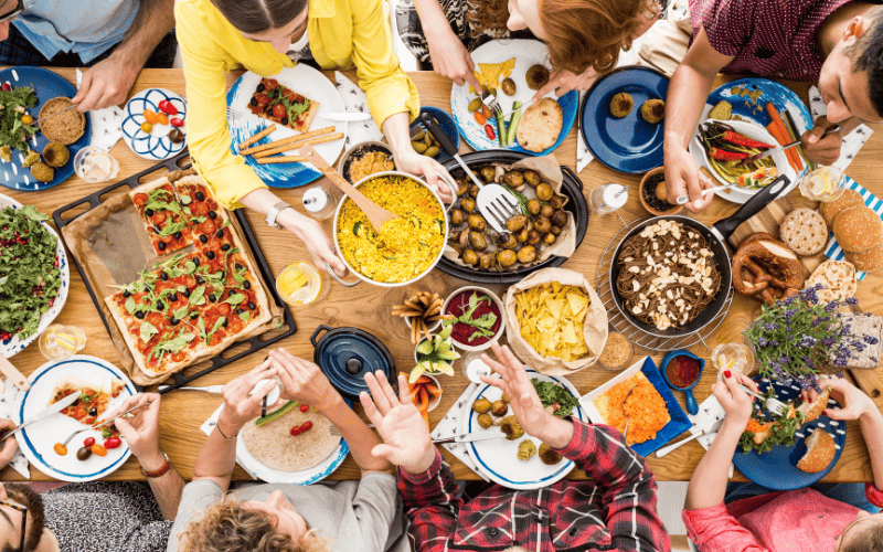 personas-compartiendo-mucha-comida-en-una-mesa
